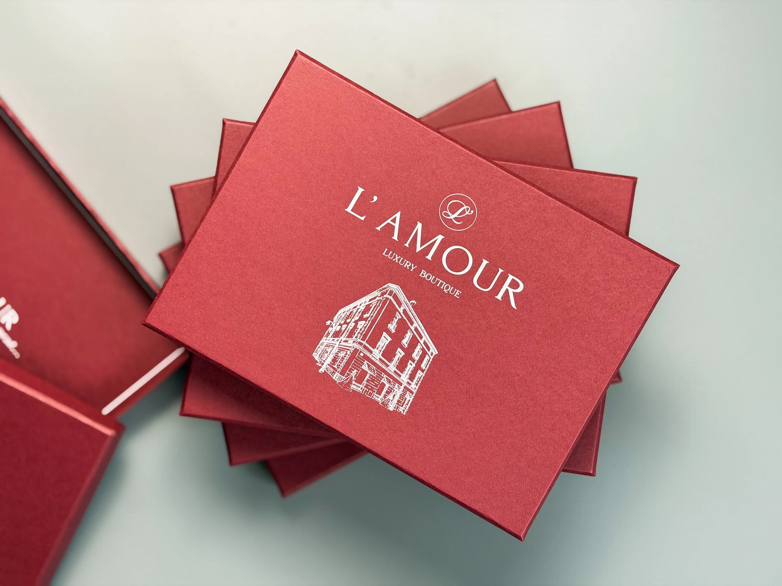 Стос бордових коробок L’AMOUR для одягу з білим логотипом