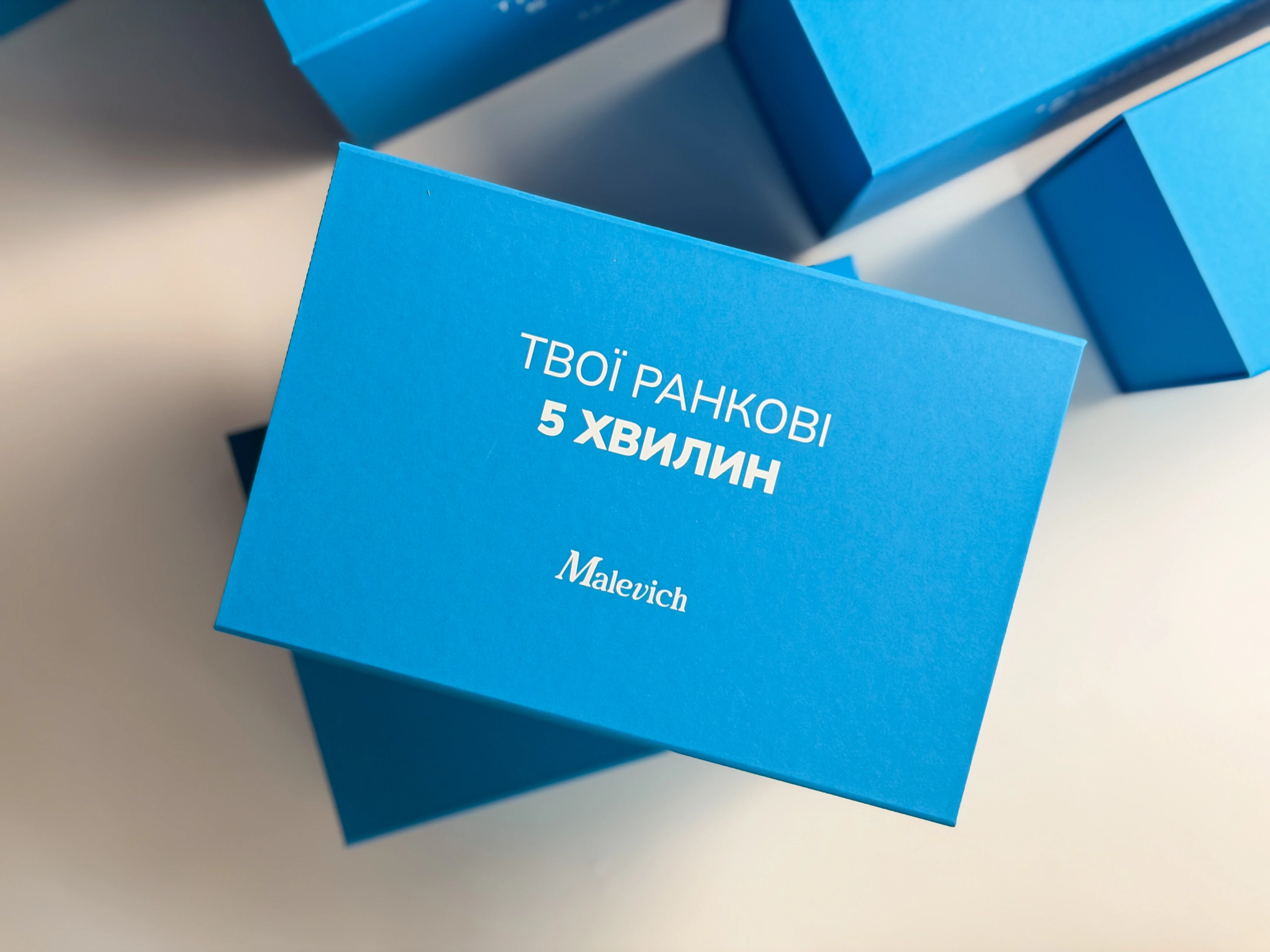 Кришка коробки Malevich з логотипом і написом білою фарбою, вигляд згори