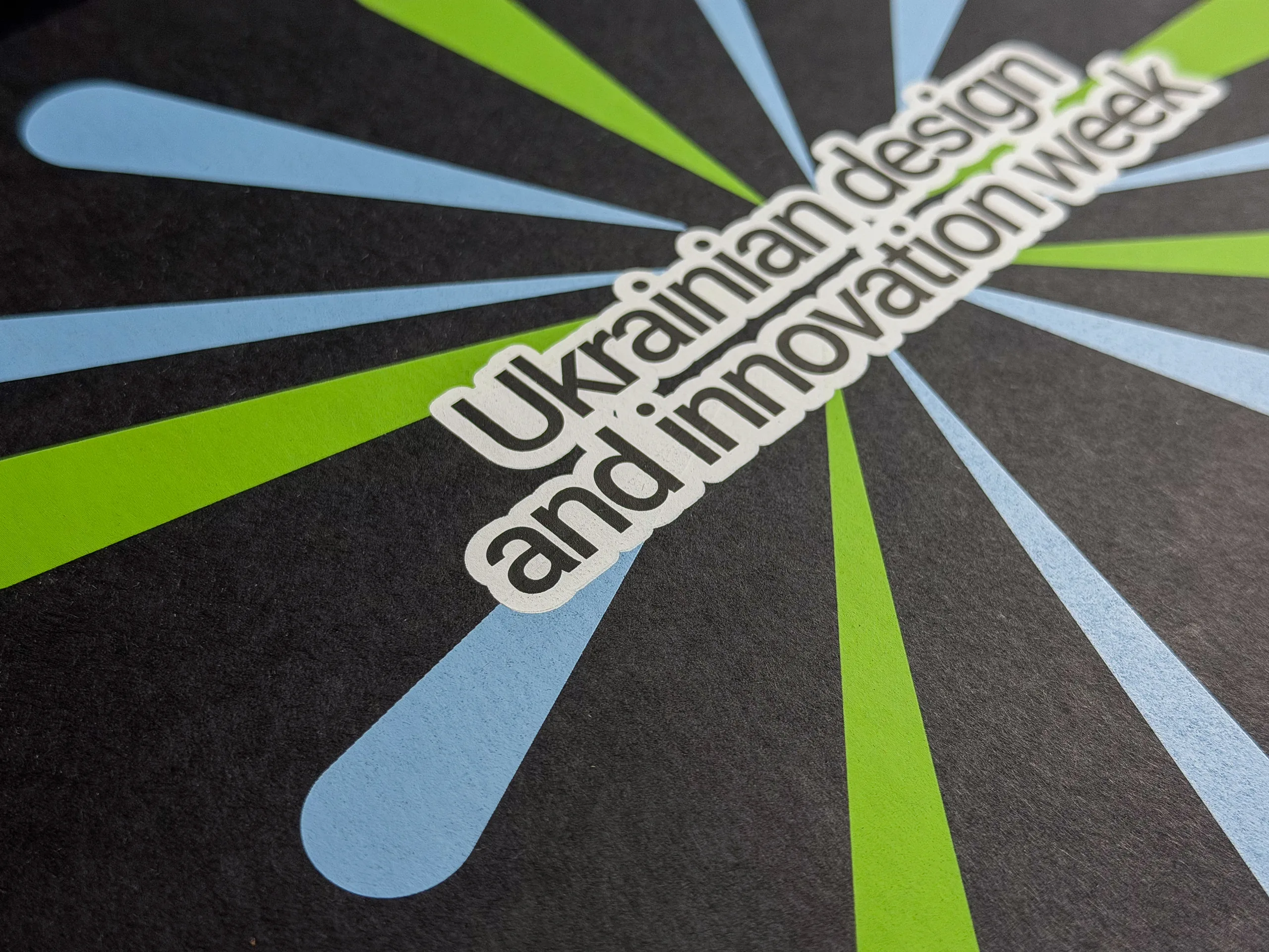 Кришка коробки Ukrainian Design крупним планом: напис і промені пантонних кольорів на чорному папері